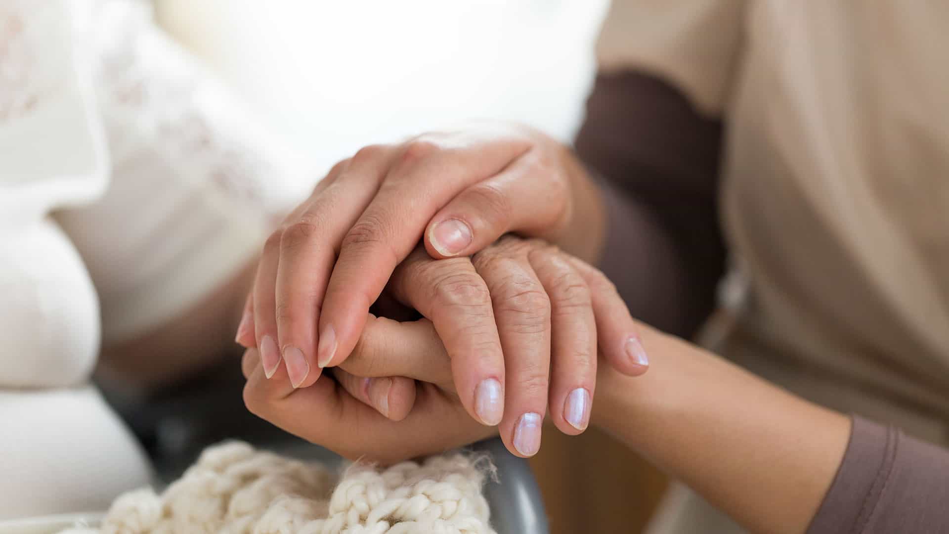 Close-up of interlocked hands of a PCW and an older adult