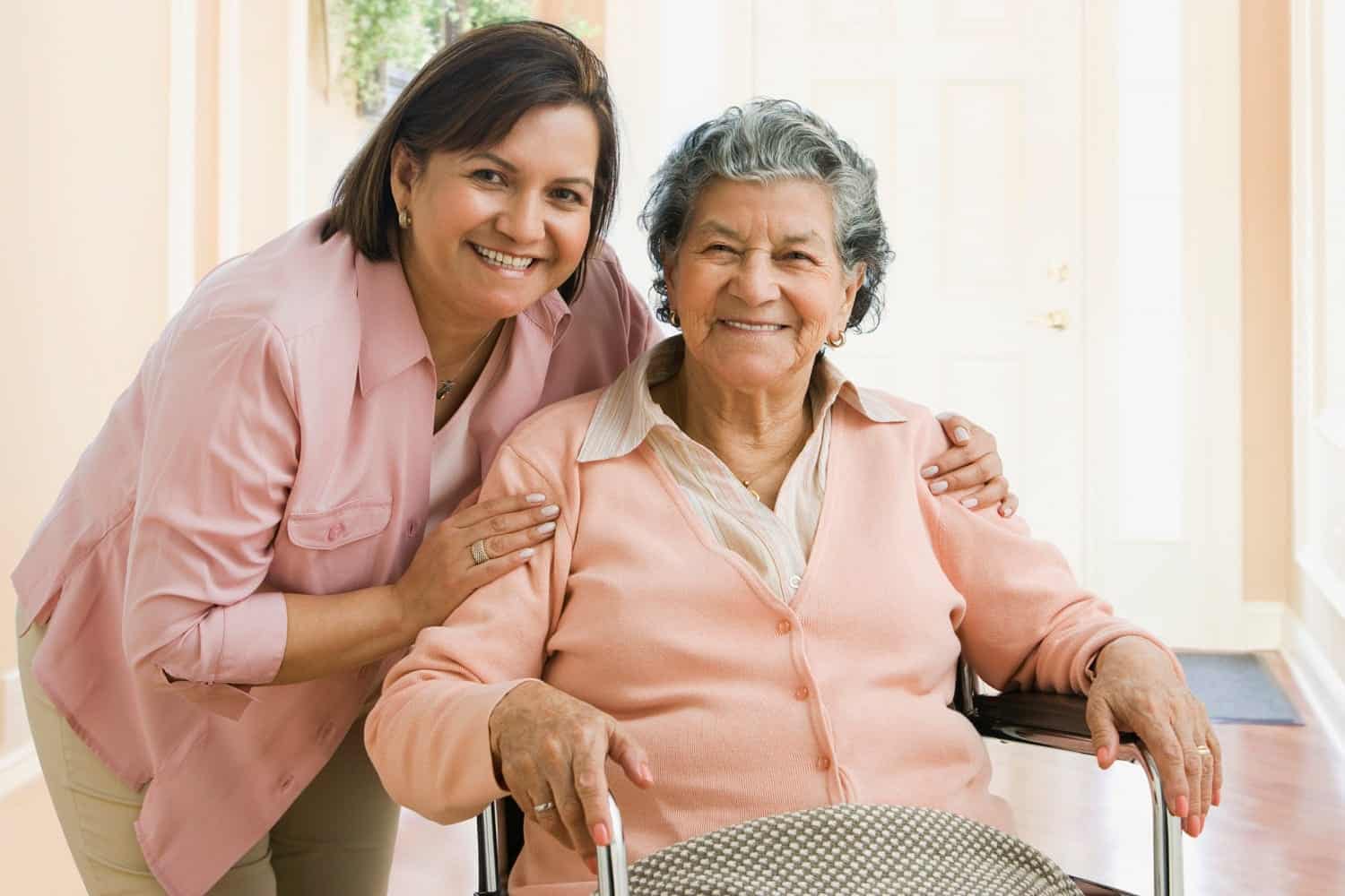 a woman in a wheel chair next to a woman in a pink shirt