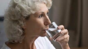 an older woman drinking water from a glass