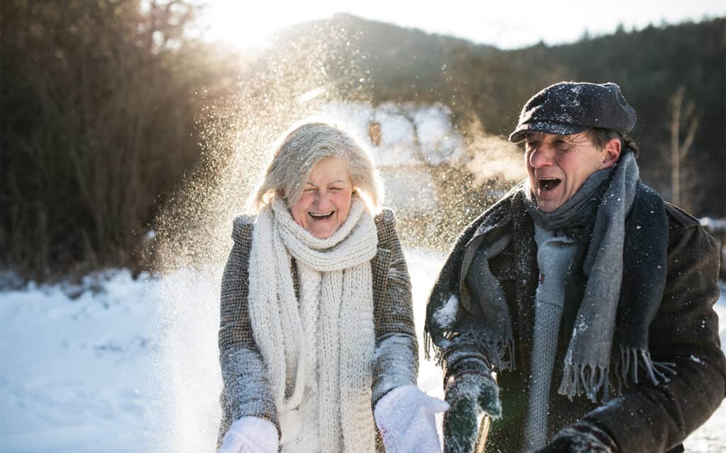 a mature man and woman playing in the snow